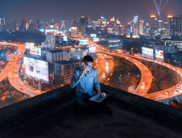 istock Asian man using phone and laptop with city  background, technology communication concept 901060454