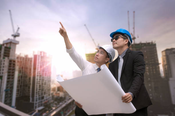 istock Asian businessman looking and point to finger away and engineer architect hold construction industrial plan background for working together as team concept 901060650