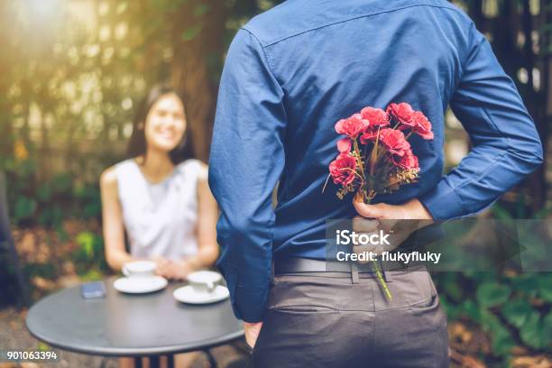 Foto de O Homem Está Escondendo As Flores Vermelhas Atrás Dele Para Surpreender Sua Namorada e mais fotos de stock de Flor