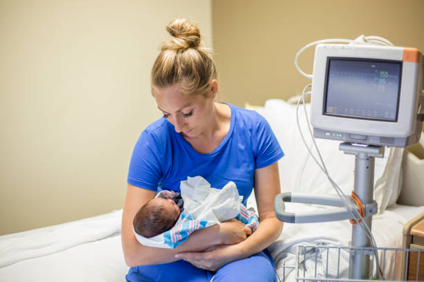 Mother holding her newborn premature baby in a hospital room stock photo
