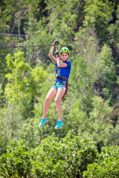 istock Smiling little girl riding a zip line through the forest 901064314