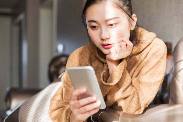 istock woman with cellphone relaxing on sofa 901071512