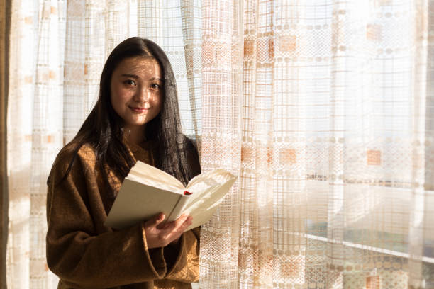 istock woman reading book by home window 901071784