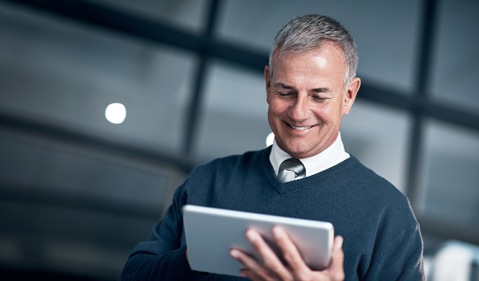 Shot of a mature businessman using a digital tablet while working late in an office