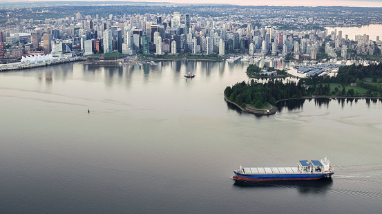 View of crowded cityscape with Canada Place, cargo ship moving in sea, Harbour Centre, Vancouver, British Columbia, Canada.
