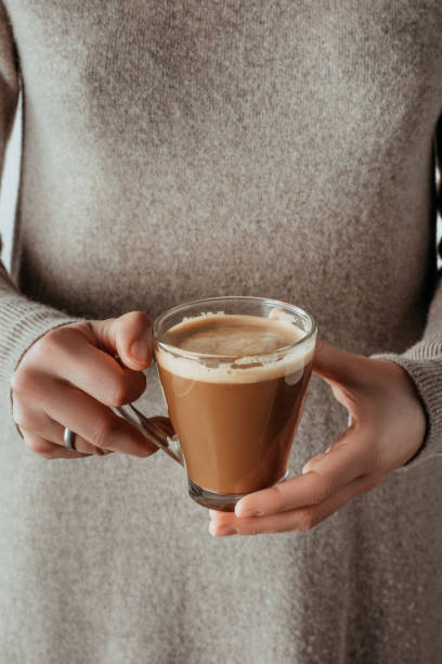 istock woman holding glass cup with coffee on grey 901089970
