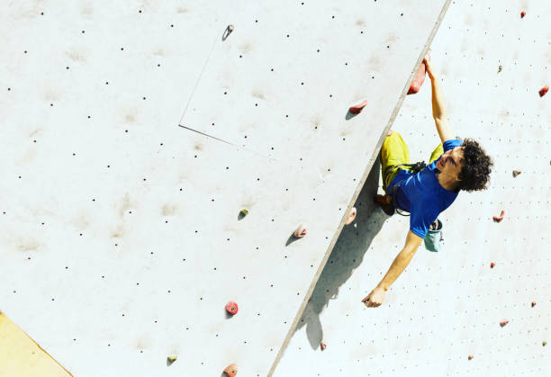 Man climber on artificial climbing wall in bouldering gym