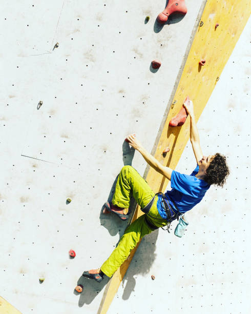 istock Man climber on artificial climbing wall in bouldering gym 901090156
