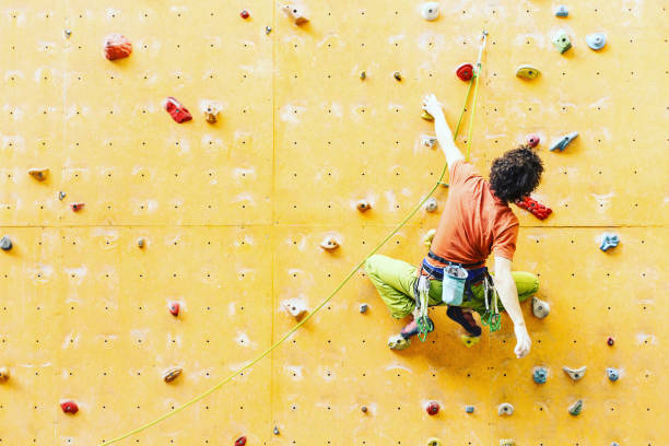 istock Man climber on artificial climbing wall in bouldering gym 901090160