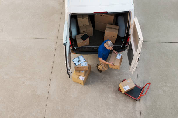 Courier delivering parcel Delivery man holding cardboard box and unloading parcel for delivery. Top view of courier unloading parcels from van. High angle view of man removing packages for the delivery. van vehicle stock pictures, royalty-free photos & images