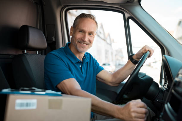 Delivery man driving van Delivery man driving van with packages on the front seat. Happy mature courier in truck. Portrait of confident express courier driving his delivery van. driver occupation stock pictures, royalty-free photos & images