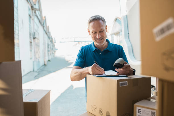 delivery man updating checklist - distribution warehouse freight transportation messenger box imagens e fotografias de stock