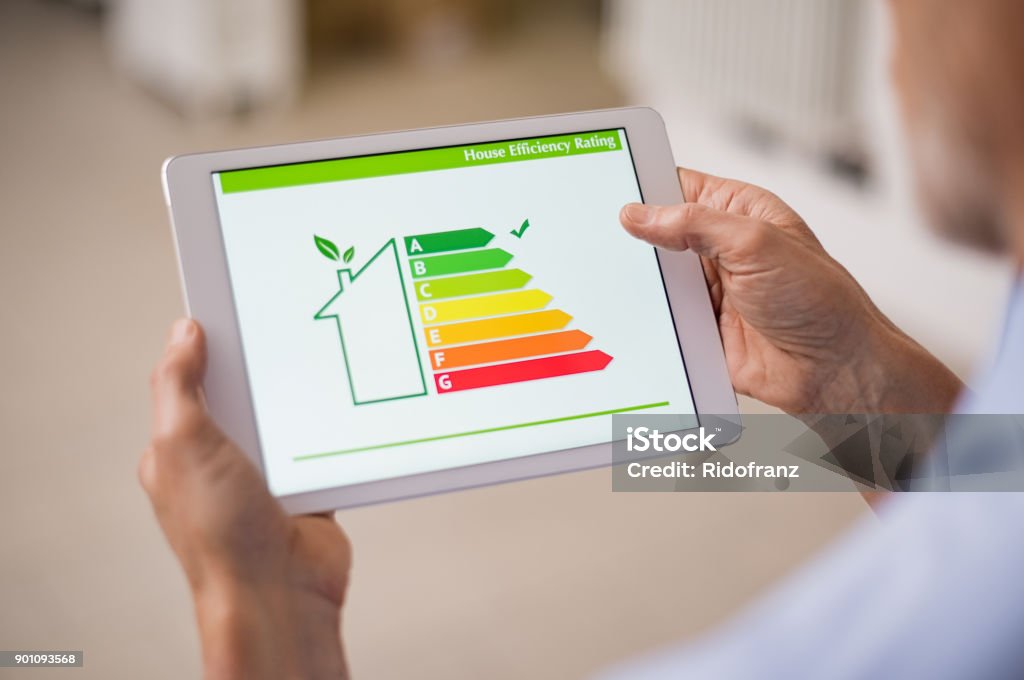 Energy efficiency house Hand holding digital tablet and looking at house efficiency rating. Detail of house efficiency rating on digital tablet screen. Concept of ecological and bio energetic house. Energy class. Energy Efficient Stock Photo