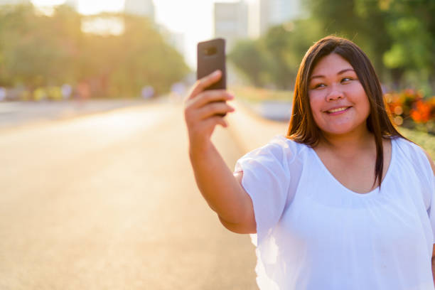 istock Beautiful Overweight Asian Woman Using Mobile Phone 901096396