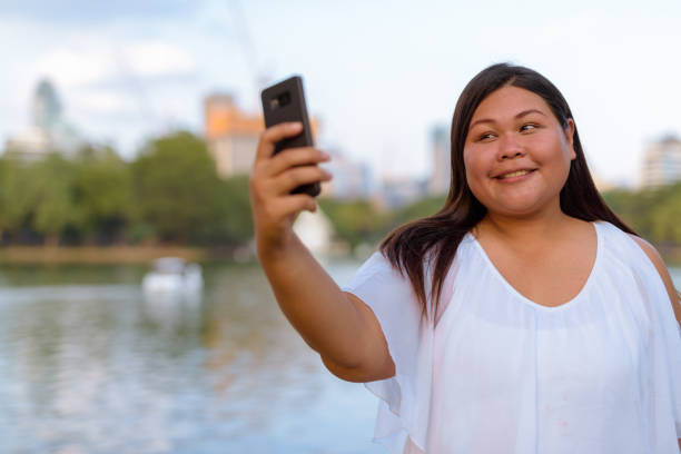 istock Beautiful Overweight Asian Woman Using Mobile Phone 901096516