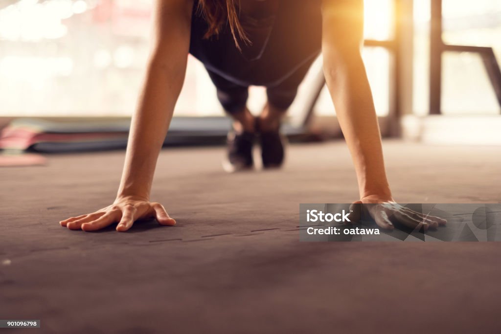 Close up woman hand doing push ups exercise in a gym in morning, sunlight effect. Exercising Stock Photo