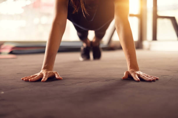 Close up woman hand doing push ups exercise in a gym in morning, sunlight effect. Close up woman hand doing push ups exercise in a gym in morning, sunlight effect. bodyweight training stock pictures, royalty-free photos & images