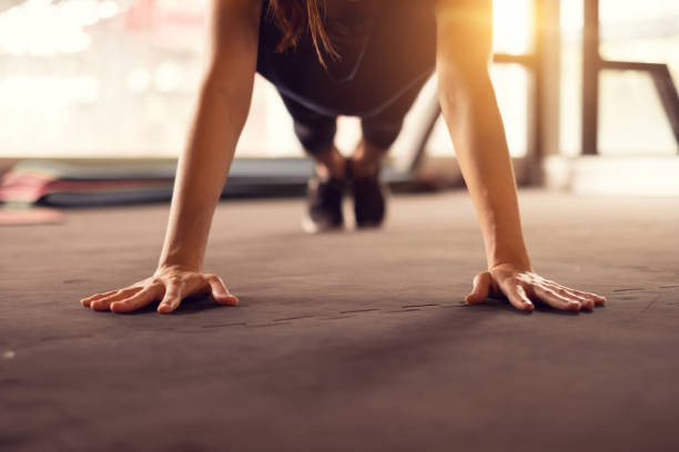 Close up woman hand doing push ups exercise in a gym in morning, sunlight effect. Close up woman hand doing push ups exercise in a gym in morning, sunlight effect. push ups stock pictures, royalty-free photos & images