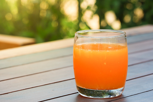 Glass cup of orange juice and a wooden reamer. Selective focus