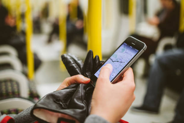 London: Woman using smartphone telephone inside metro tube station with map navigation application on the screen open and searching for the next destination - wagon interior