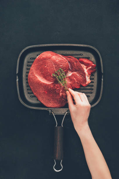 istock woman putting herb onto raw steak on grill pan 901108302