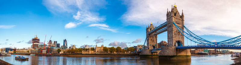 Panoramic London skyline with iconic symbol, the Tower Bridge and Her Majesty's Royal Palace and Fortress, known as the Tower of London as viewed from South Bank of the River Thames in the morning light