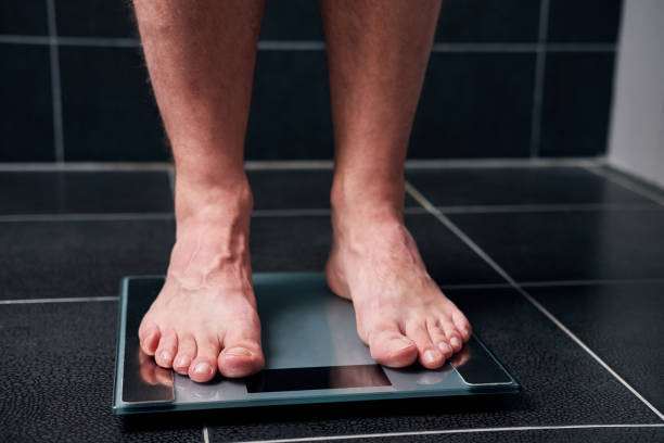 Male feet on the scale Male feet on the scale in the bathroom low body fat stock pictures, royalty-free photos & images