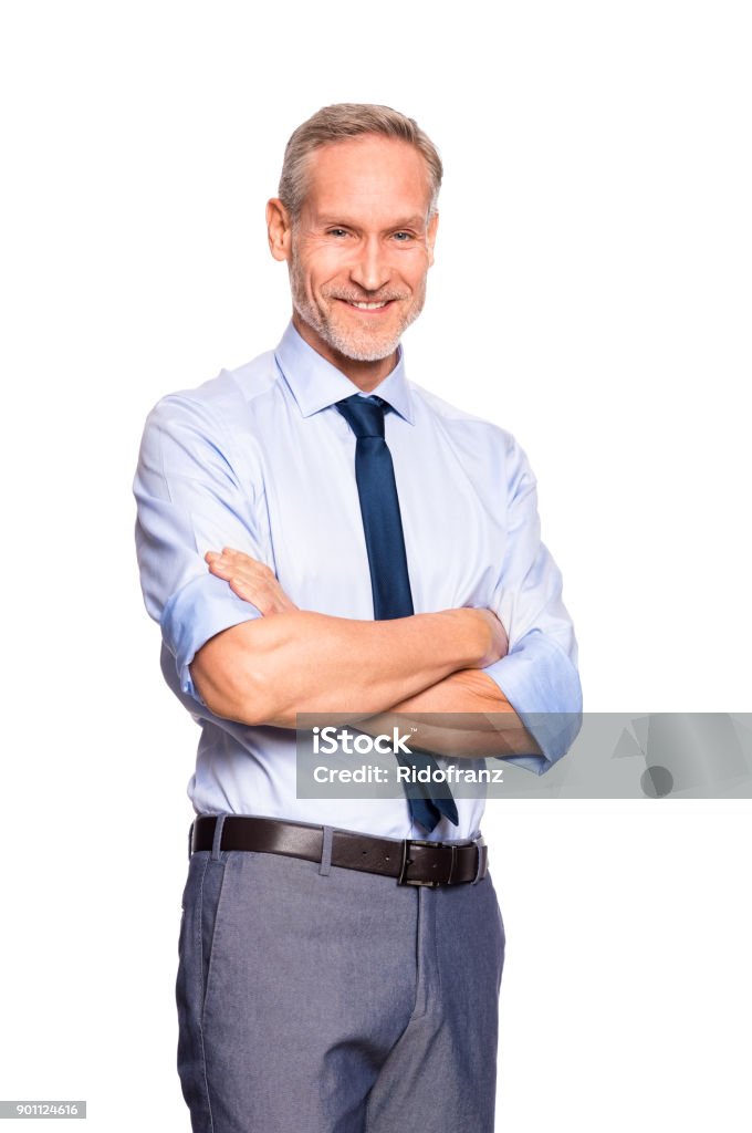 Successful senior businessman Portrait of successful mature businessman looking at camera isolated on white background. Cheerful senior business man standing with crossed arms. Smiling manager in formal isolated over white background. White Background Stock Photo