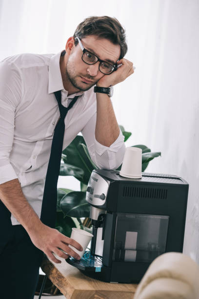 istock bored overworked businessman pouring coffee from office machine 901126102