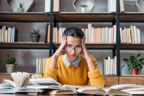 istock girl preparing for exam at library and holding head 901131312