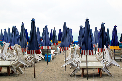 The empty beach with a lot of sunbeds and umbrellas in a rainy weather. Pattaya, Thailand.