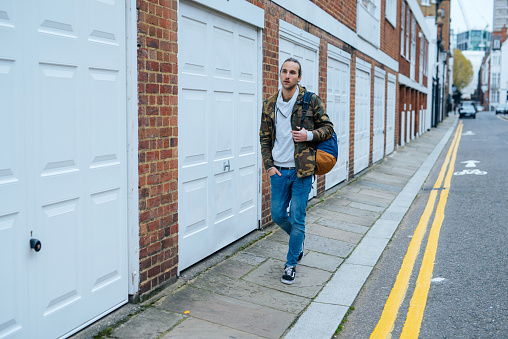 Portrait of young British guy on the streets of London in autumn. Man has long hair and green eyes, dressed in casual clothing. He got used to live a metrpoloitan living and enjoys it.