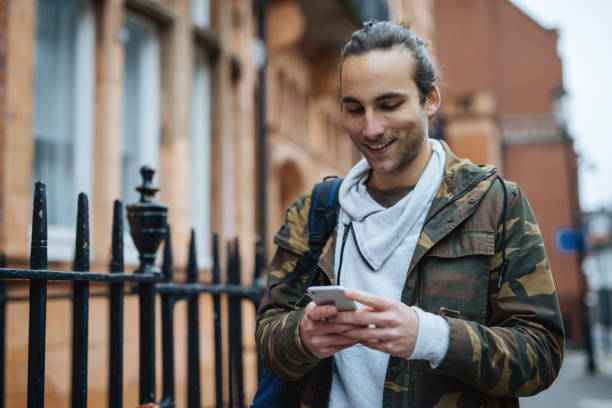 istock Cheerful guy walking in the street and using smart phone 901140854