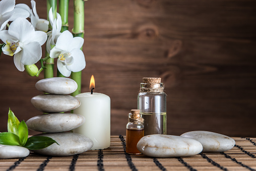 massage oil ,white zen  balance stones,orchid and bamboo leaves on the wooden table