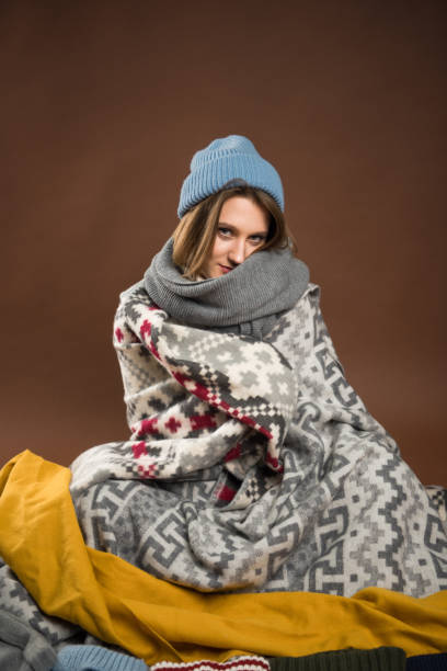 istock Woman sitting wrapped in blankets 901146272