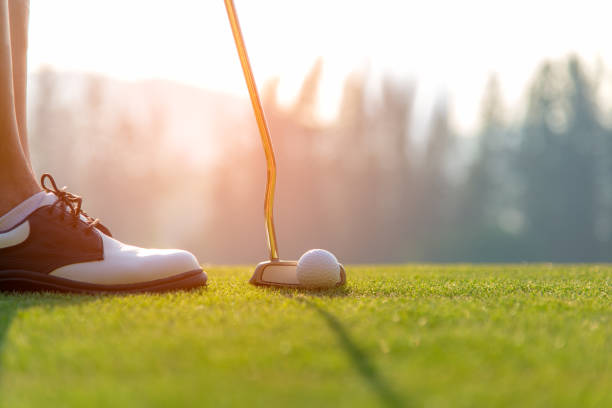 golfer asiatin putting golfball auf dem grünen golf auf sonne eingestellt am abendzeit.  gesunde und lifestyle-konzept. - einlochen stock-fotos und bilder