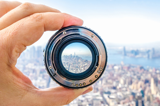 Hand holding camera lens in New York City. USA