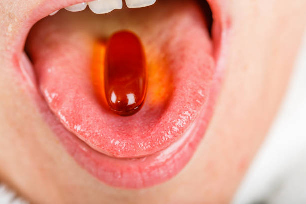 istock Fish oil capsule in mouth 901178048