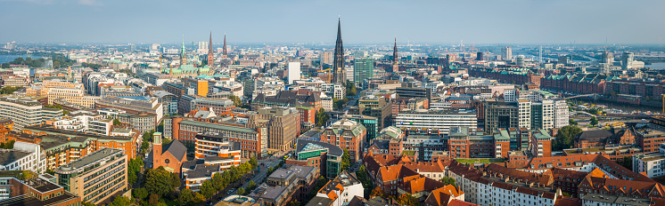 Aerial panorama over the spires and rooftops of central Hamburg, from the iconic tower of the Rathaus to the warehouses of Speicherstadt and the Elbe beyond, Germany.