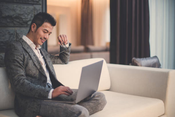 Modern businessman using laptop Businessman sitting on the sofa and using laptop wealthy lifestyle stock pictures, royalty-free photos & images