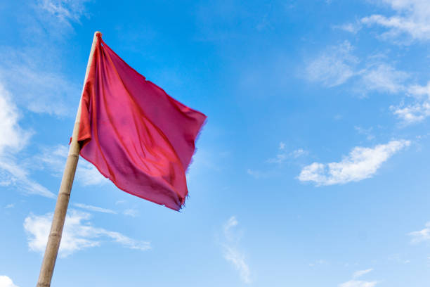 istock Red Flag against blue sky with clouds 901191516