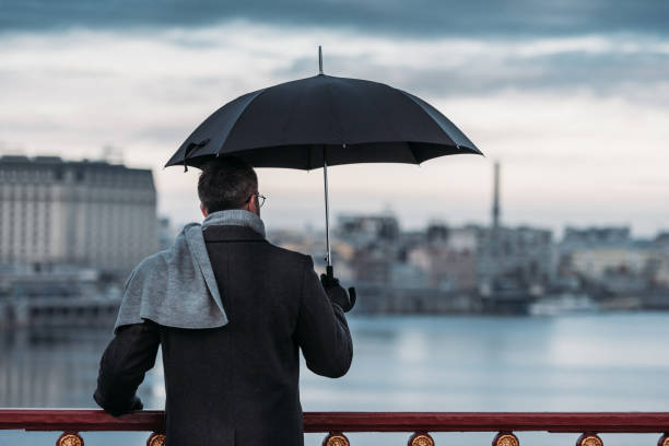 istock back view of lonely man with umbrella standing on bridge 901193884