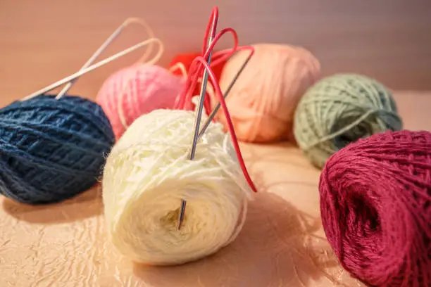 Knitting wool and a woolen ball - as a concept of hobbies and handmade creativity. Colored woolen threads in a tangle on a light background. 