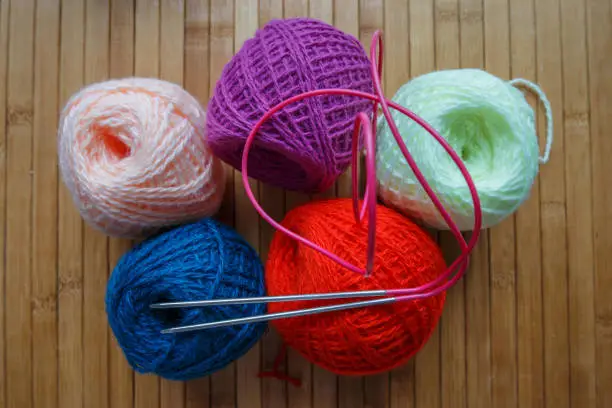 Knitting wool and a woolen ball - as a concept of hobbies and handmade creativity. Colored woolen threads in a tangle on a light background.