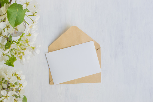 Mockup white greeting card and envelope with white spring flowers and light background