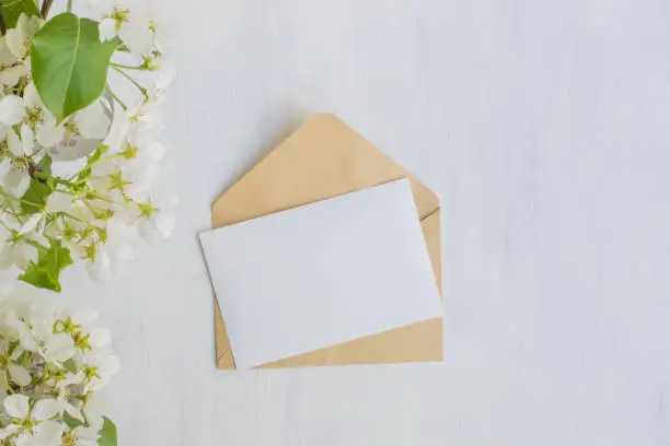 Photo of Mockup white greeting card with white spring flowers