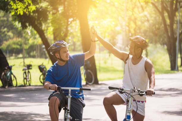 istock Friends are touching hands together while cycling together in a shady park. 901199032