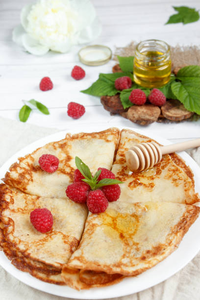 istock Thin pancakes with honey and raspberries on a white plate 901199220