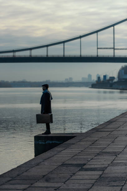 istock handsome adult man in coat with suitcase standing on river shore 901199362