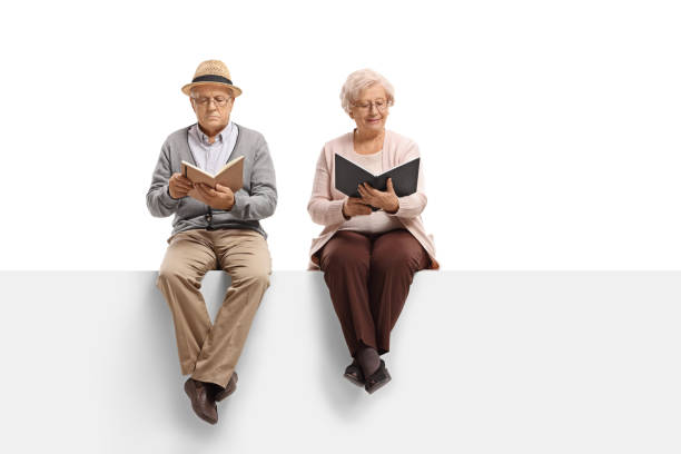 Mature man and an elderly woman sitting on a panel and reading books isolated on white background